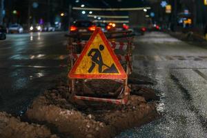 Road works ahead sign at winter night street near pit photo