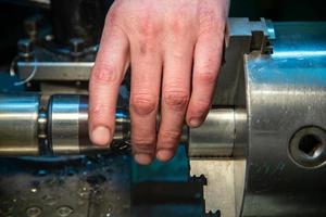 turner hand setting workpiece in 3-jaw chuck of small metalworking lathe photo