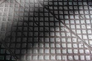 old cast iron industrial floor tiles with checkered skid-proof pattern - factory background photo