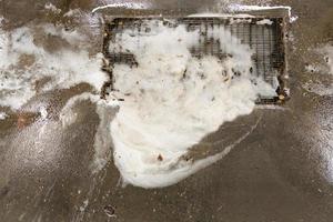 clogged floor grate with dirty soap sud at outdoor self-service car wash station photo
