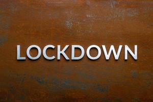 the word lockdown laid with silver metal letters on flat rusted steel sheet background in directly above perspective photo