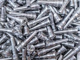 Full frame background of pile of shiny long steel parts, clean steel rods after fine cnc turning - laying chaotically with selective focus. photo