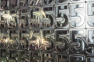 shiny metal machined digit 5 plates tiled tightly - full frame background photo