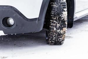 an unadorned picture of winter car wheel with metal spikes on snow close-up photo