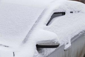 coche plateado cubierto con una gruesa capa de nieve a la luz del día nublado - primer plano foto