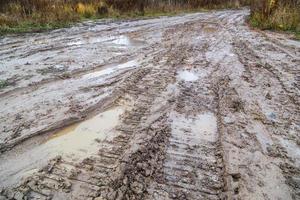 camino de barro de arcilla sucia con huellas de neumáticos - primer plano con enfoque selectivo y desenfoque foto