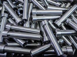 pile of shiny steel tubes after cnc turning operations - abstract full frame indistrial background photo