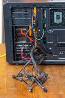 un montón de cables de computadora que sobresalen de la caja de pc negra abierta - primer plano con enfoque selectivo foto