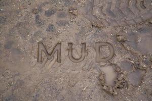 the word mud imprinted in wet dirt road surface - close-up with selective focus photo