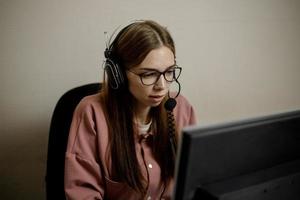 A serious call center operator is talking to a client while looking at a computer screen in close-up. photo