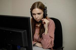 A serious call center operator is talking to a client while looking at a computer screen in close-up. photo