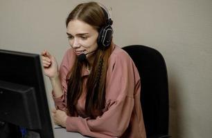 un feliz agente del centro de llamadas que trabaja en una línea directa de soporte en la oficina. un operador del centro de llamadas está hablando con un cliente mientras mira una pantalla de computadora en primer plano foto