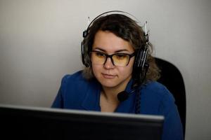 A serious call center operator is talking to a client while looking at a computer screen in close-up. photo