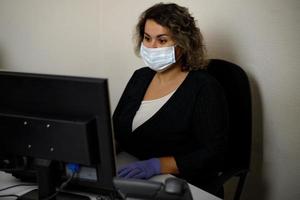 A serious call center operator is talking to a client while looking at a computer screen in close-up. photo