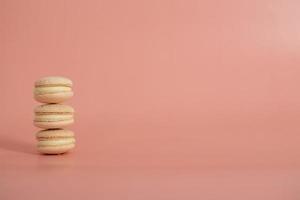 hermosos macarrones dulces redondos sobre un fondo rosa. Bodegón con pasteles de macarrones y flores diferentes. copie el espacio bandera foto