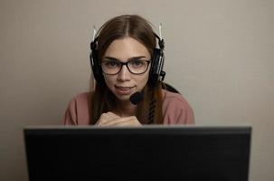 A happy call center agent working on a support hotline in the office. A call center operator is talking to a customer while looking at a computer screen in close-up photo
