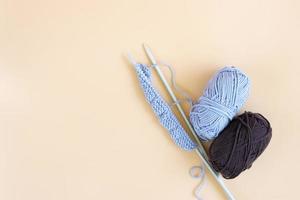 Top view of gray knitting wool and knitting needles on pastel orange background. photo