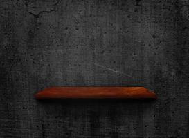 espacio en blanco de un viejo estante de madera sobre un fondo de textura de pared oscura con un camino de recorte para el diseño foto