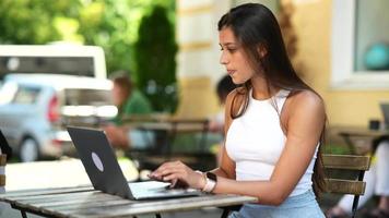 mulher senta-se no café ao ar livre usando laptop video