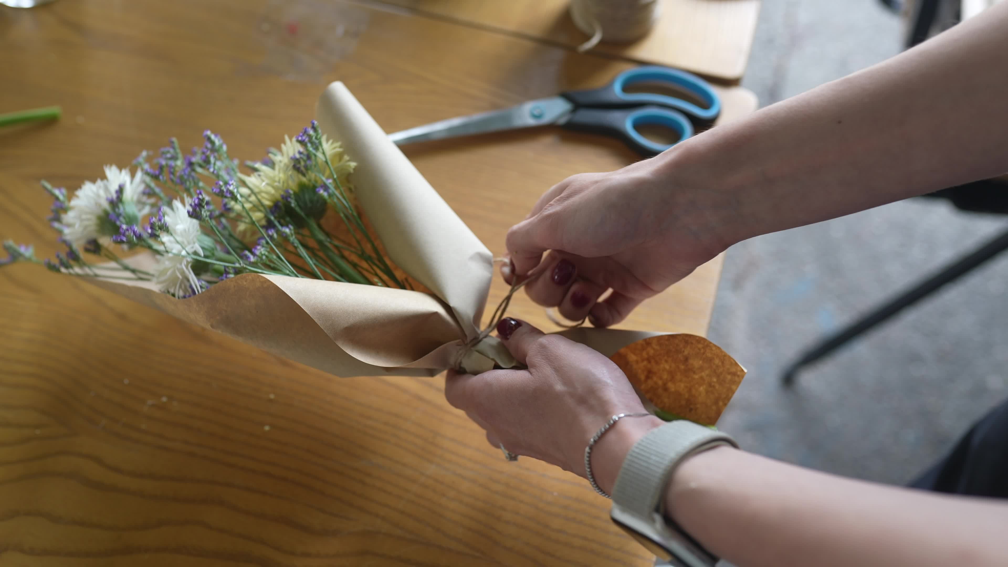 Florist wraps flower bouquet in brown paper and twine 12678287 Stock Video  at Vecteezy