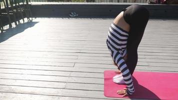 Pan around woman stretching on yoga mat on an outdoor deck video