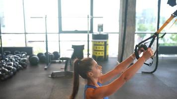 Young fit woman exercises in gym using equipment video