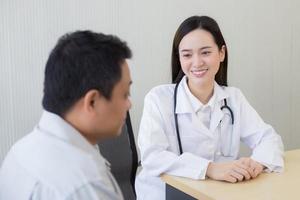una doctora asiática sonríe y anima a un paciente hombre. foto