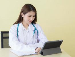 Asian woman doctor searching information about patient on her tablet photo