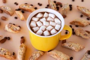 Cup with black coffee with marshmallows and cookies cantuccini, decorated almond and coffee beans on pink background. photo