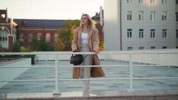 portret, gelukkig bedrijf vrouw in een bruin jas wandelingen in de stad herfst park. carrière mensen. mode, schoonheid. vrouw portretten. echt mensen. langzaam beweging video