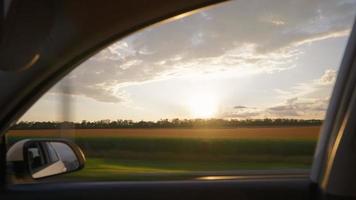 visie van de kant venster van een auto het rijden snel langs de snelweg gedurende een mooi zonsondergang. reizen reis en avontuur concept. video