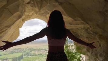 View from the Back Silhouette of a Happy Woman Traveler Raising Her Hands to the Side in a Cave. Success and Active Lifestyle. Travel and Motivation Concept. Go Everywhere. Slow Motion. video