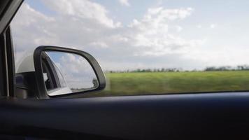 Blick vom Seitenspiegel auf das Innere eines fahrenden Autos entlang der Autobahn an einem sonnigen Tag. Konzept von Fahrzeugen und Transport. keine Leute. video