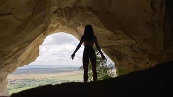 Sportlerin klettert in die Höhle. Mädchen geht durch eine atemberaubende Höhle. reise- und abenteuerkonzept. Zeitlupe. video