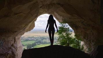 viajante atlético mulher sobe a caverna. garota caminha por uma caverna deslumbrante. conceito de viagens e aventura. câmera lenta.