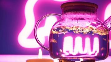 A transparent kettle boils on a gas burner against a neon purple backlight. Blurred bubbles in hot water boiling inside a glass teapot. video