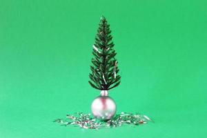 Christmas decorations - shiny silver ball artificial Christmas tree with a silver tinsel on green background with copy space. Minimal Christmas and New Year concept. photo