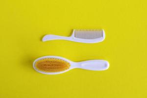 White hairbrush and comb for baby on white background, flat lay with copy space. Baby care concept. photo