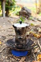 cafetera de géiser con café caliente recién hecho en un quemador de gas portátil en un camping.