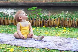 linda niña caucásica con vestido amarillo está mirando hacia arriba. picnic en un día soleado de verano en el parque. foto