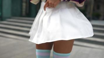 Woman in short white skirt and letterman jacket spins outside video