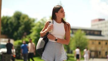 une femme marche sur un chemin extérieur portant un sac à dos par une journée ensoleillée video