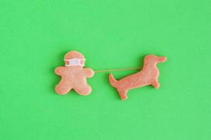 Homemade shortbread cookies with white glaze on green background, top view. Man with face mask is walking with dog. photo