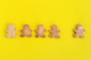 Galletas caseras de pan dulce con glaseado blanco sobre fondo amarillo, vista superior. multitud de personas y un hombre con mascarilla. foto