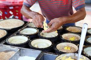 Unrecognizable man is cooking traditional Malaysian street food apam balik - thick soft pancake with peanuts, bananas, peanut butter and sweet corn. Street market in Georgetown, Malaysia. photo