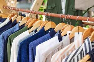 Wooden clothes racks with colorful male suits on hangers. Showcase with clothes on street market. photo