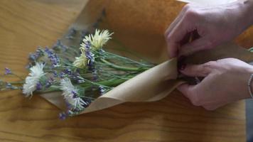 floristería envuelve ramo de flores en papel marrón y cordel video