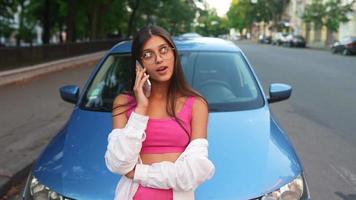 femme s'appuie sur le capot de la voiture en parlant au téléphone video