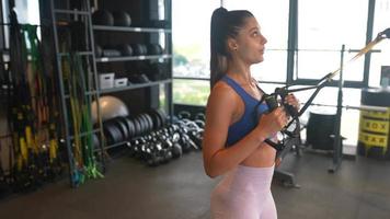 Ejercicios de mujer joven en el gimnasio usando equipo video