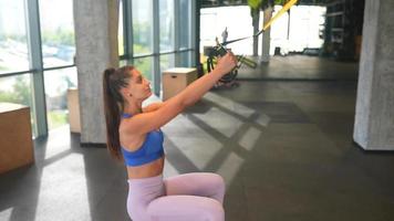 Young fit woman exercises in gym using equipment